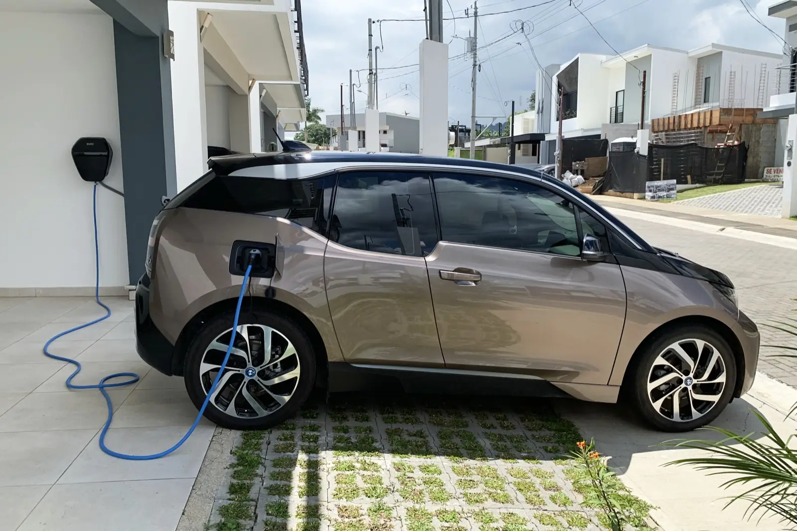 Auto elettrica in ricarica da una wallbox installata sulla parete di casa